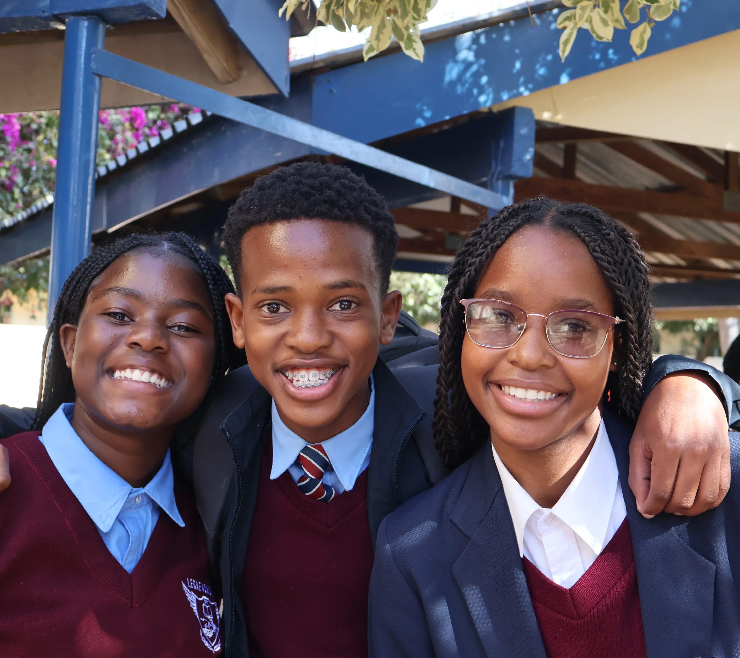 Three school students smiling together in uniform